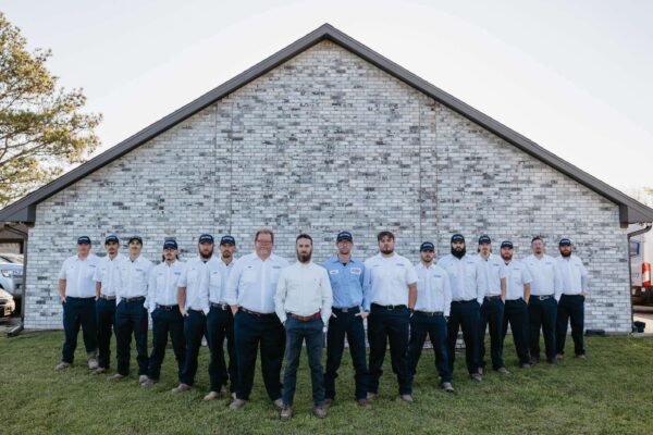 The Dusty Underwood Team Lined Up In Front Of A Brick House.