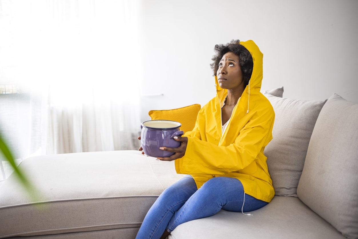 A man in yellow gloves performing plumbing maintenance outdoors.