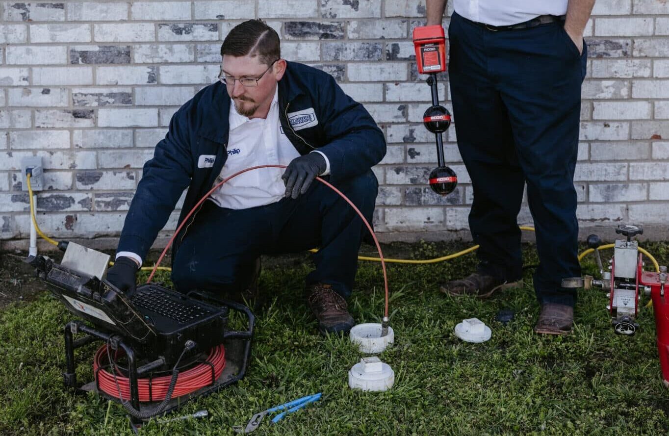 Two plumbers at Dusty Underwood Plumbing using hydro jetting on a clogged drain.