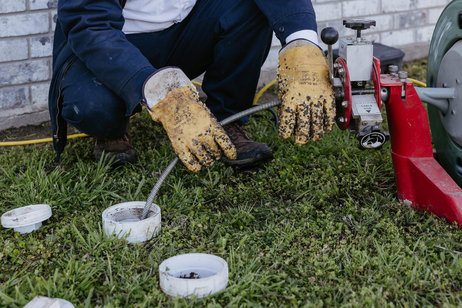 One of the members of the Dusty Underwood team cleaning an outdoor pipe with a hydrojetter.