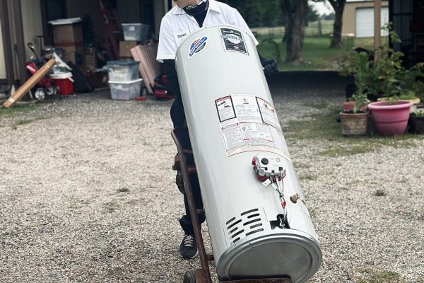 A Plumber From Underwood Plumbing & Septic Wheeling In A New Water Heater To A Texas Home.